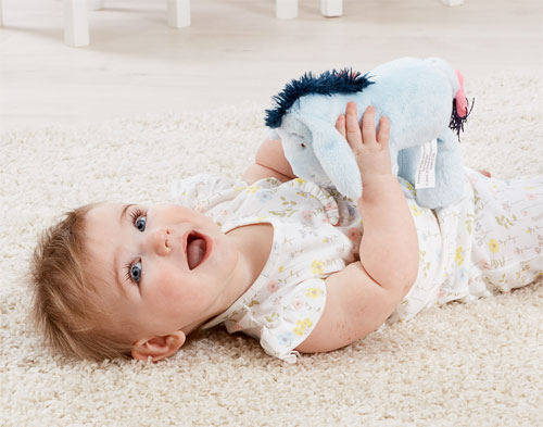 Baby cuddling Eeyore soft toy